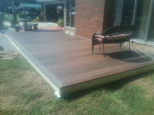 New wood deck and wicker chair beside a brick house in Covington